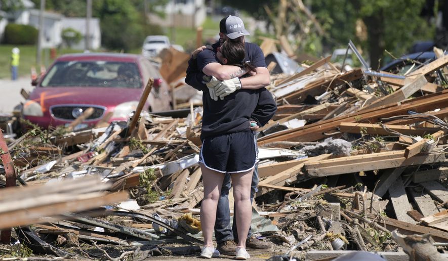 Local residents hug in front of their tornado damaged home, Wednesday, May 22, 2024, in Greenfield, Iowa. (AP Photo/Charlie Neibergall)