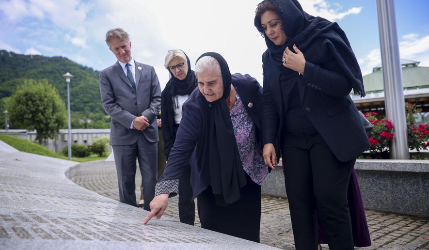 UK Minister of State (Minister for Europe) Nusrat Ghani, right, walks with Munira Subasic, president of the association Mother of Srebrenica, centre, next to the momument with the names of Srebrenica genocide victims, at the Memorial Center in Potocari, Bosnia, Wednesday, May 22, 2024. On May 23, the United Nations General Assembly will be voting on a draft resolution declaring July 11 the International Day of Reflection and Commemoration of the 1995 genocide in Srebrenica. (AP Photo/Armin Durgut)