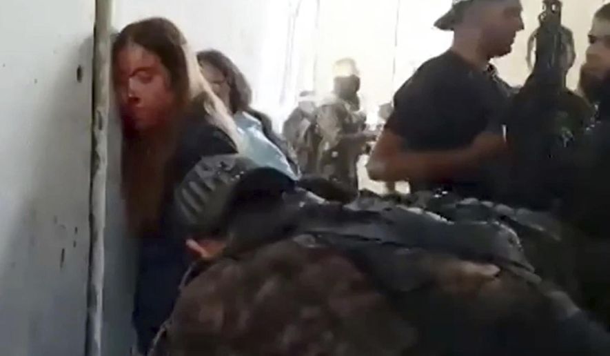 In this image taken from video provided by the Hostage Families Forum, Israeli female soldiers from the Nahal Oz military base are placed against the wall and shackled by members of Hamas after they were taken captive on Oct. 7, 2023. The footage was taken by Hamas militants who stormed the Nahal Oz military base, part of the militant group’s wider assault on southern Israel that killed roughly 1,200 people and took about 250 others hostage. (Hostage Families Forum via AP)