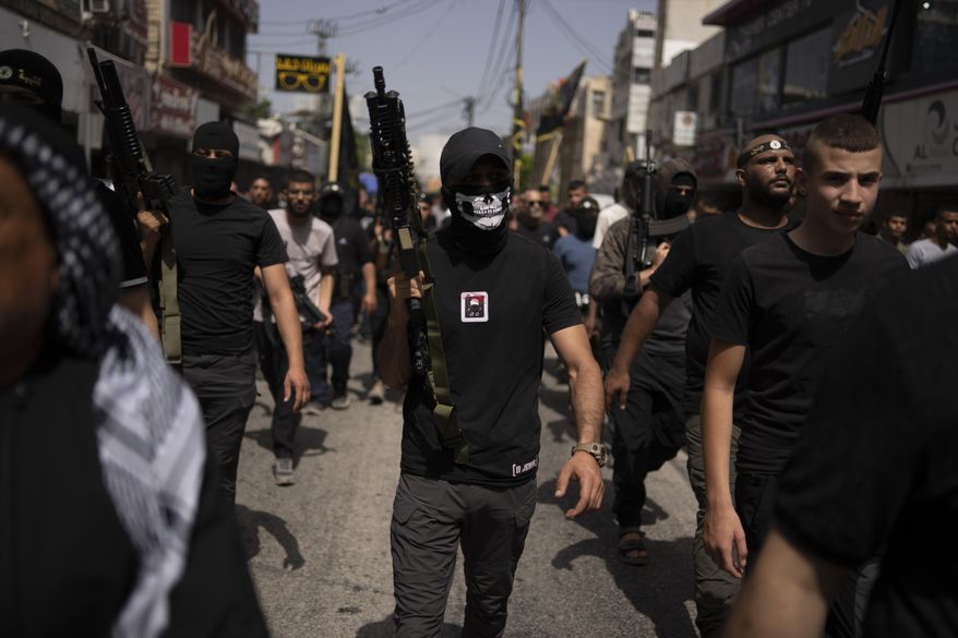 Gunmen march as mourners carry the bodies of Palestinians, some draped in the Islamic Jihad militant group flags during their funeral in the West Bank city of Jenin, Thursday, May 23, 2024. The Israeli military said Thursday it has completed a two-day operation in the occupied West Bank that the Palestinian Health Ministry says killed 12 Palestinians. Militant groups claimed at least eight of the dead as fighters, one from Hamas and seven from the Al-Aqsa Martyrs Brigade. (AP Photo/Leo Correa)
