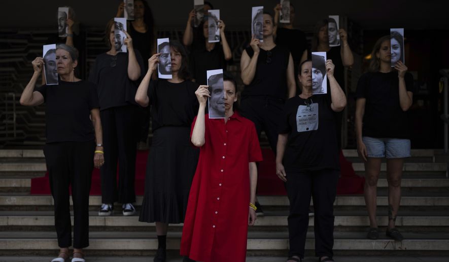 Relatives and supporters of Israeli hostages held by Hamas in Gaza hold photos of their loved ones during a performance calling for their return in Tel Aviv, Israel, Thursday, May 23, 2024. (AP Photo/Oded Balilty)