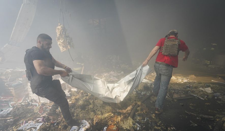 Rescuers carry a body after a Russian missile hit a large printing house in Kharkiv, Ukraine, Thursday, May 23, 2024. Russian missiles slammed into Ukraine’s second-largest city in the northeast of the country and killed at least seven civilians early Thursday, officials said, as Kyiv’s army labored to hold off an intense cross-border offensive by the Kremlin’s larger and better-equipped forces. (AP Photo/Andrii Marienko)