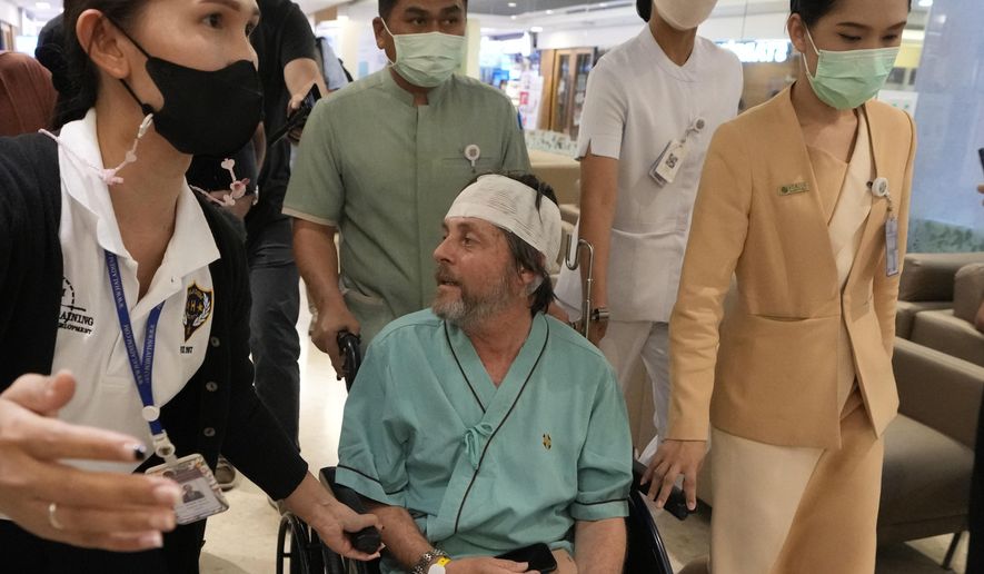 An Australian passenger, center, who was injured on a flight that was battered by severe turbulence, talks to reporters at Samitivej Srinakarin Hospital in Bangkok, Thailand, Thursday, May 23, 2024. The airline's Flight SQ321 was flying from London’s Heathrow airport to Singapore when it hit the turbulence Tuesday, bashing people around inside the plane. (AP Photo/Sakchai Lalit)