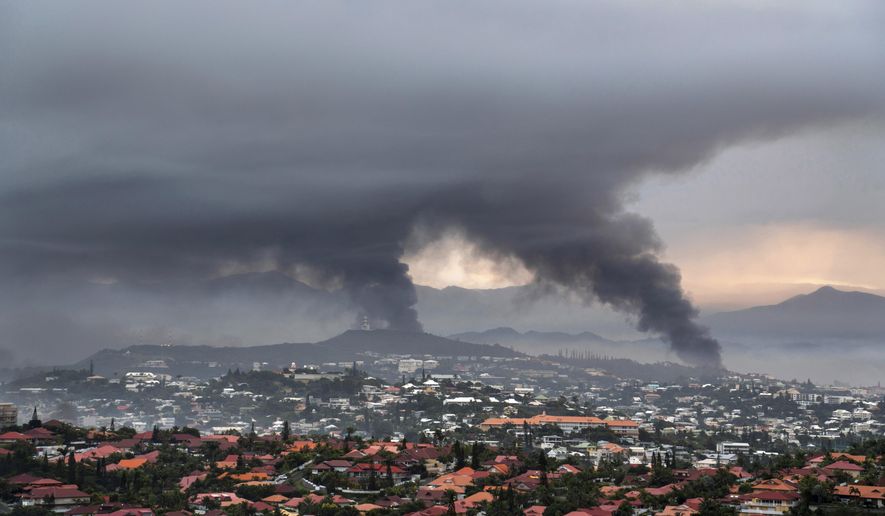 Smoke rises during protests in Noumea, New Caledonia, Wednesday May 15, 2024. France has imposed a state of emergency in the French Pacific territory of New Caledonia. The French prosecutor for New Caledonia says there's been another shooting death in the riot-hit French Pacific territory, with a police officer taken into custody after using their firearm Friday May 24, 2024 when they were set upon by a group of about 15 people. It comes a day after French President Emmanuel Macron made an emergency round-trip from Paris to de-escalate the violence in New Caledonia where Indigenous Kanak people have long sought independence from France. (AP Photo/Nicolas Job, File)