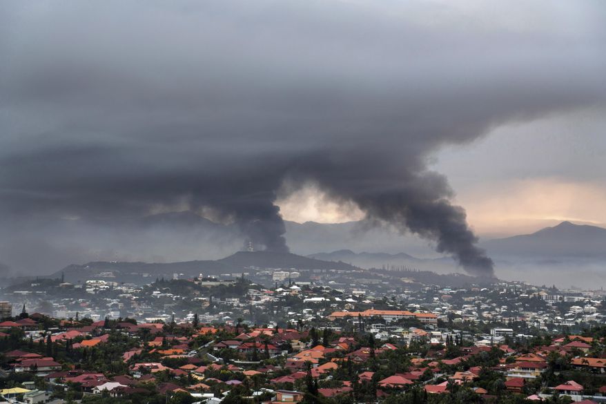 Smoke rises during protests in Noumea, New Caledonia, Wednesday May 15, 2024. France has imposed a state of emergency in the French Pacific territory of New Caledonia. The French prosecutor for New Caledonia says there's been another shooting death in the riot-hit French Pacific territory, with a police officer taken into custody after using their firearm Friday May 24, 2024 when they were set upon by a group of about 15 people. It comes a day after French President Emmanuel Macron made an emergency round-trip from Paris to de-escalate the violence in New Caledonia where Indigenous Kanak people have long sought independence from France. (AP Photo/Nicolas Job, File)