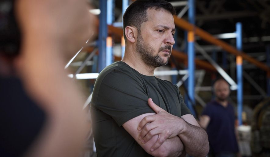 Ukraine's President Volodymyr Zelenskyy looks at burnt books in a damaged workshop of Ukraine's largest printing house ruined in Thursday deadly Russian missile attack that killed seven civilians in Kharkiv, Ukraine, Friday, May 24, 2024. (Ukrainian Presidential Press Office via AP)