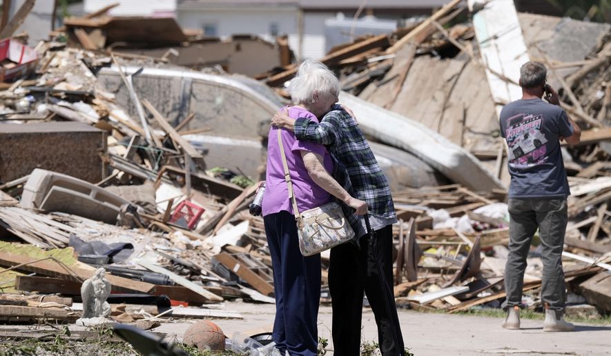 Joan Mitchell, left, gets a hug from her neighbor Edith Schaecher in front of their tornado damaged homes, Thursday, May 23, 2024, in Greenfield, Iowa. (AP Photo/Charlie Neibergall)