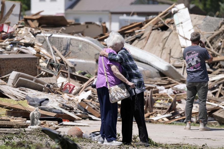 Joan Mitchell, left, gets a hug from her neighbor Edith Schaecher in front of their tornado damaged homes, Thursday, May 23, 2024, in Greenfield, Iowa. (AP Photo/Charlie Neibergall)