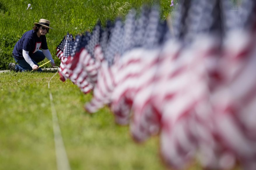 A volunteer helps put up a field of flags near the War Memorial Thursday, May 23, 2024, in Milwaukee. The Memorial Day tribute will feature 27,316 American flags representing Wisconsin residents who paid the ultimate price for freedom in service to our nation. (AP Photo/Morry Gash)