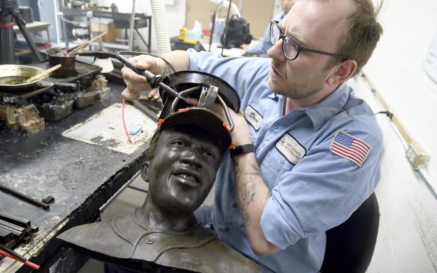 David Hobbs, an employee at Art Castings of Colorado, touches up a wax mold of Jackie Robinson's head in Loveland, Colo. on Wednesday, May 8, 2024. The original statue was cut off at the ankles and stolen from a park in Wichita, Kansas in January. The Colorado foundry cast that sculpture in 2019 and, luckily, still had the original plaster and rubber molds. (AP Photo/Thomas Peipert)