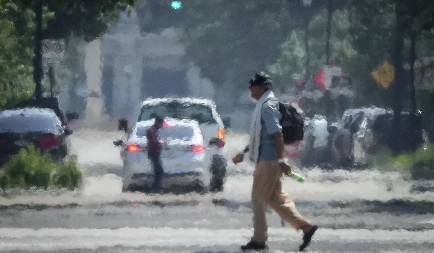 A person crosses Caroline Street in the afternoon heat Saturday, May 25, 2024, near Discovery Green in Downtown Houston. (Jon Shapley/Houston Chronicle via AP)