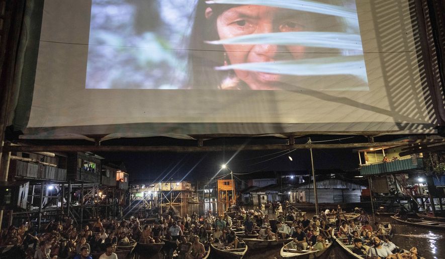 Spectators watch from boats a film projected on a screen set up on a wooden structure during the Muyuna Floating Film Festival, that celebrares tropical forests, in the Belen neighborhood of Iquitos, Peru, Saturday, May 25, 2024. (AP Photo/Rodrigo Abd)
