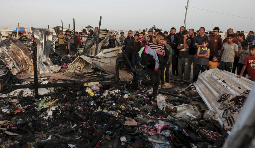 Palestinians look at the destruction after an Israeli strike where displaced people were staying in Rafah, Gaza Strip, Monday, May 27, 2024. Palestinian health workers said Israeli airstrikes killed at least 35 people in the area. Israel's army confirmed Sunday's strike and said it hit a Hamas installation and killed two senior Hamas militants. (AP Photo/Jehad Alshrafi)