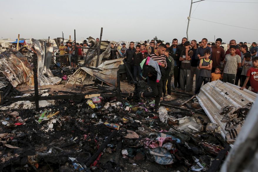 Palestinians look at the destruction after an Israeli strike where displaced people were staying in Rafah, Gaza Strip, Monday, May 27, 2024. Palestinian health workers said Israeli airstrikes killed at least 35 people in the area. Israel's army confirmed Sunday's strike and said it hit a Hamas installation and killed two senior Hamas militants. (AP Photo/Jehad Alshrafi)