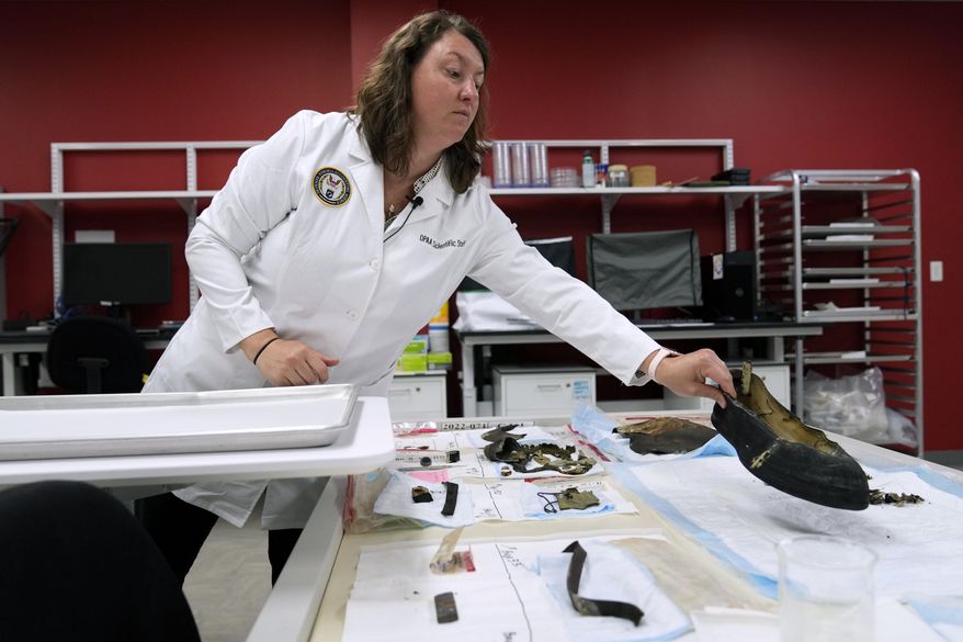 Defense POW/MIA Accounting Agency forensic anthropologist Carrie Brown looks at objects in a lab at Offutt Air Force Base, Monday, May 20, 2024, in Bellevue, Neb. Generations of American families have grown up without ever knowing exactly what happened to their loved ones who served in the military. But a lab tucked away above the bowling alley on Offutt Air Force Base in the Omaha suburbs and a sister lab in Hawaii that are part of the federal DPAA are steadily answering those lingering questions and offering about 200 families a year the chance to honor their relatives with a proper burial. (AP Photo/Charlie Neibergall)
