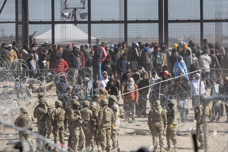 Texas National Guard watch migrants after beaching barriers set up on the Rio Grande in El Paso, Texas, March 21, 2024. (Omar Ornelas/El Paso Times via Associated Press)