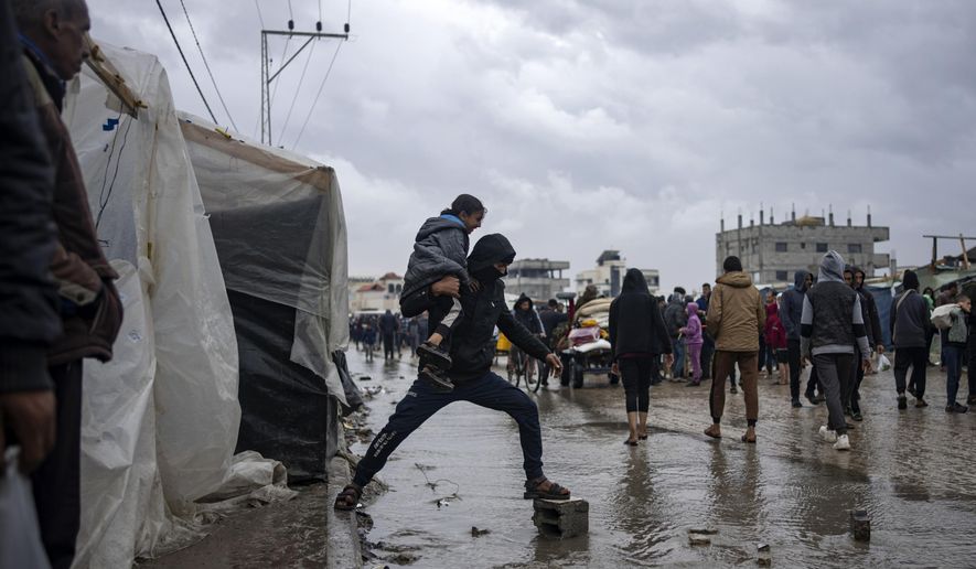 Palestinians displaced by the Israeli air and ground offensive on the Gaza Strip walk through a makeshift tent camp in Rafah on Jan. 27, 2024. The tent camps stretch for more than 16 kilometers (10 miles) along Gaza’s coast, filling the beach and sprawling into empty lots, fields and town streets. (AP Photo/Fatima Shbair, File)