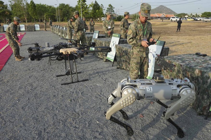 A Chinese army man, right, tests a machine gun equipped on a robot dog before participating in the Golden Dragon military exercise in Svay Chok village, Kampong Chhnang province, north of Phnom Penh Cambodia, Thursday, May 16, 2024. Cambodia and China on Thursday kicked off their annual Golden Dragon military exercise to strengthen cooperation and exchange military experiences. (AP Photo/Heng Sinith)