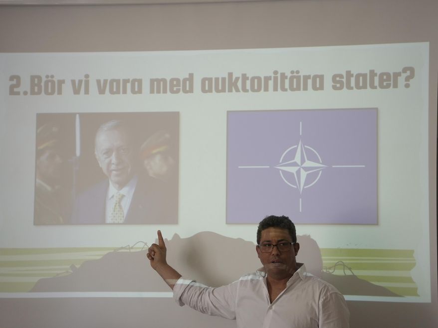 Masai Bjoerkwall, a junior high school teacher at Viktor Rydberg's School, teaches the history of NATO and the implications of Sweden joining NATO, in Stockholm, Sweden, Friday, May 17, 2024. Slogan reads “Should we be with authoritarian states?” (AP Photo/Chisato Tanaka)