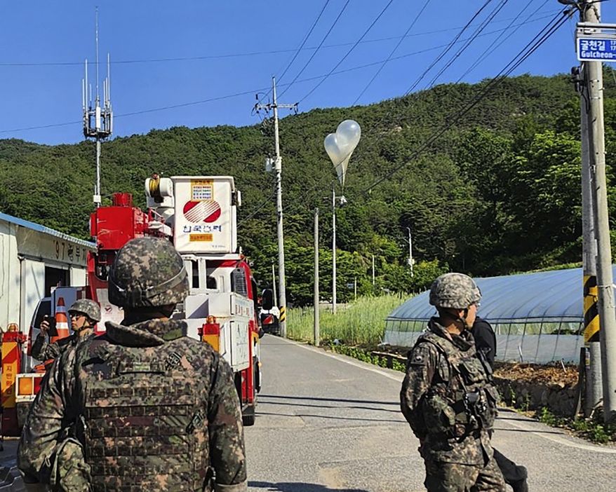 In this photo provided by Jeonbuk Fire Headquarters, balloons with trash presumably sent by North Korea, hang on electric wires as South Korean army soldiers stand guard in Muju, South Korea, on Wednesday, May 29, 2024. (Jeonbuk Fire Headquarters via AP, File)