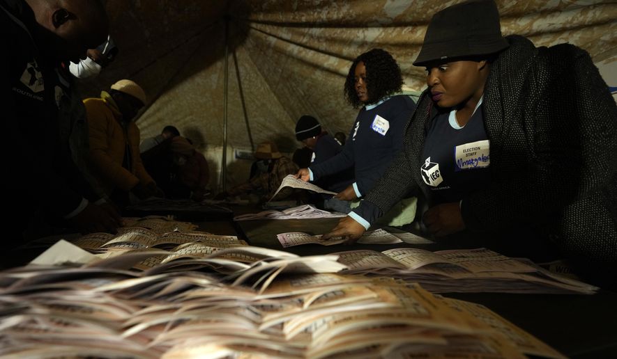 Electoral workers check ballot papers during the counting at a polling station at Itireleng informal settlement in Pretoria, South Africa, Wednesday, May 29, 2024, during the general elections. South Africans voted Wednesday at schools, community centers, and in large white tents set up in open fields in an election seen as their country’s most important since apartheid ended 30 years ago. It could put the young democracy into unknown territory. (AP Photo/Themba Hadebe)