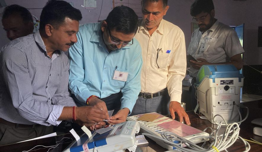 Polling officials check and seal an electronic voting machine before they allow voters to cast their votes at a polling station during the last round of a six week-long national election near Dharamshala, India, Saturday, June 1, 2024. The seventh round of voting in 57 constituencies across seven states and one union territory will complete polling for all 543 seats in the powerful lower house of parliament. Nearly 970 million voters more than 10% of the world's population were eligible to elect a new parliament for five years. (AP Photo/Ashwini Bhatia)