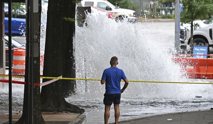 Joe Greene watches a water main break Saturday, June 1, 2024, in Atlanta. City officials were slowly repressuring the city's water system Saturday after corroding water pipes burst in downtown and Midtown, forcing many businesses and attractions to close and affecting water service in area homes. (Hyosub Shin/Atlanta Journal-Constitution via AP)