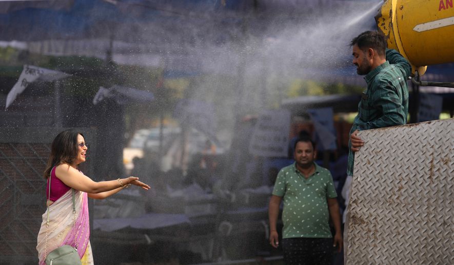 A polling official enjoys a cooling spray of water under intense heat at a distribution venue for Electronic Voting Machines (EVMs) and other election material on the eve of the fifth phase of polling in the six-week-long national election in Lucknow, India, Sunday, May 19, 2024. A top United Nations official says even though climate change makes disasters such as cyclones, floods and droughts more intense, more frequent and striking more places, fewer people are dying from those catastrophes globally. Thats because of better warning, planning and resilience. (AP Photo/Rajesh Kumar Singh, File)