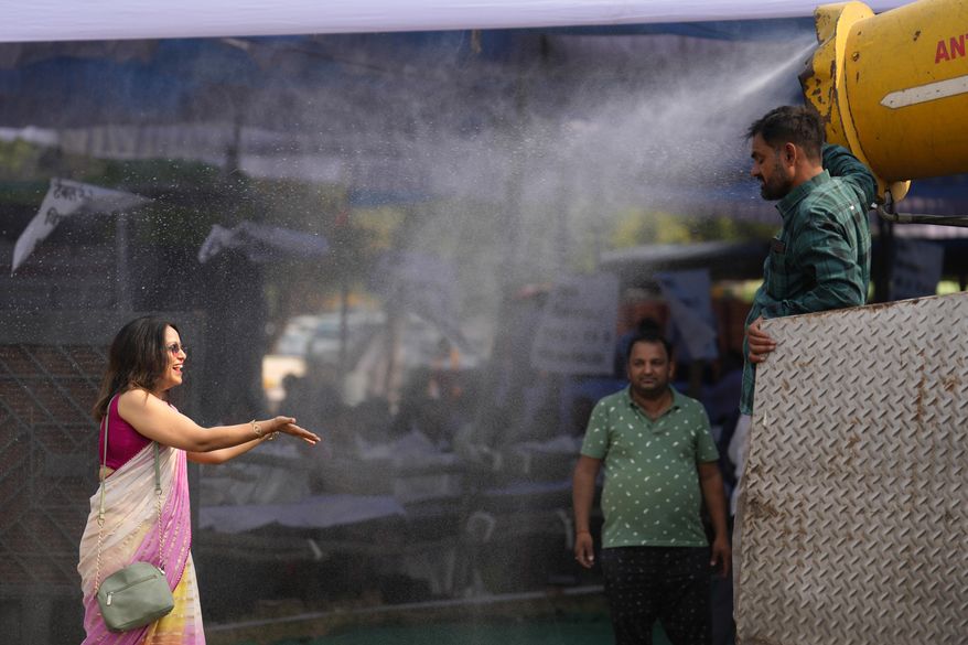 A polling official enjoys a cooling spray of water under intense heat at a distribution venue for Electronic Voting Machines (EVMs) and other election material on the eve of the fifth phase of polling in the six-week-long national election in Lucknow, India, Sunday, May 19, 2024. A top United Nations official says even though climate change makes disasters such as cyclones, floods and droughts more intense, more frequent and striking more places, fewer people are dying from those catastrophes globally. Thats because of better warning, planning and resilience. (AP Photo/Rajesh Kumar Singh, File)