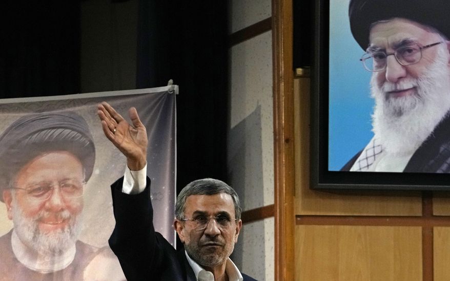 Iran's hard-line former President Mahmoud Ahmadinejad waves to the media as he leaves at the conclusion of a press briefing beside portraits of the Supreme Leader Ayatollah Ali Khamenei, top right, and the late President Ebrahim Raisi after registering his name as a candidate for the June 28 presidential election at the Interior Ministry, in Tehran, Iran, Sunday, June 2, 2024. Ahmadinejad registered Sunday as a possible candidate for the presidential election, seeking to regain the country's top political position after a helicopter crash killed the nation's president. (AP Photo/Vahid Salemi)