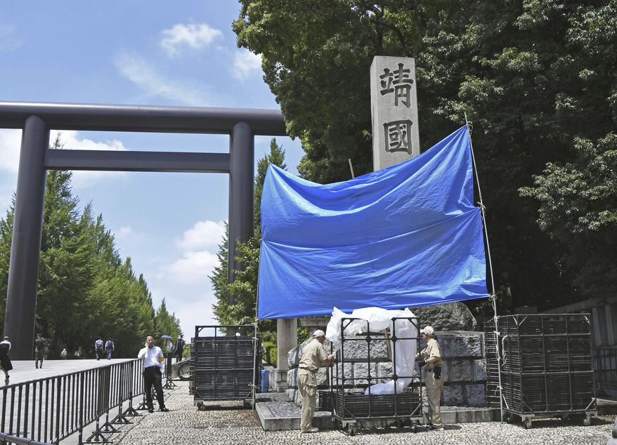 Workers attend to removing a graffiti on Yasukuni Shrine's stone pillar, covered under blue sheet in Tokyo, on June 1, 2024.(Kyodo News via AP)