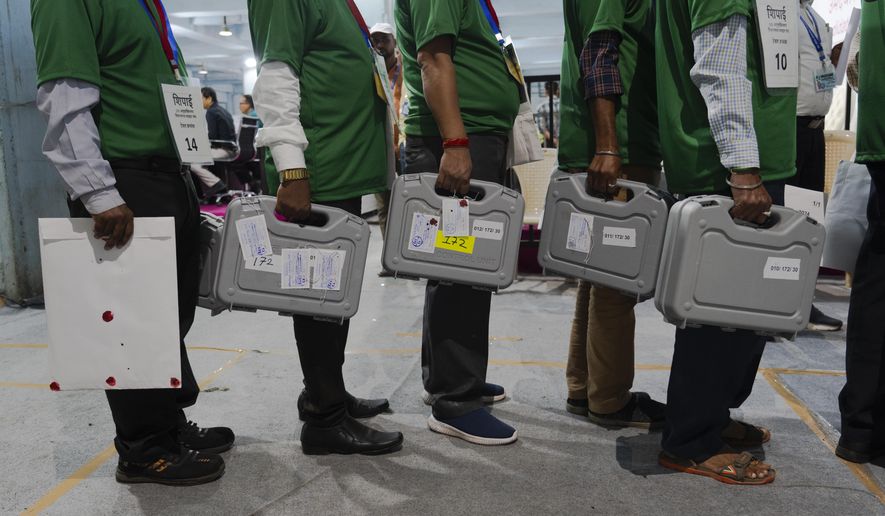 Election officials carry sealed electronic voting machines at a counting center in Mumbai, India, Tuesday, June 4, 2024. India on Tuesday started counting votes from its staggered, six-week election that was seen as a referendum on Prime Minister Narendra Modi's decade in power and was expected to give him a third term in office. (AP Photo/Rafiq Maqbool)