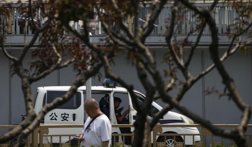 A man walks by a security and a policeman sit inside a police van stationed at a bridge along the Chang'an Avenue in Beijing, Tuesday, June 4, 2024. China has quashed large-scale commemorations of Tuesday's 35th anniversary of Beijing's Tiananmen Square crackdown within its borders. But outside the country, commemorative events have grown increasingly crucial for preserving memories of the 1989 bloodletting, in which government troops opened fire on pro-democracy protesters resulting in hundreds, if not thousands, dead. (AP Photo/Andy Wong)