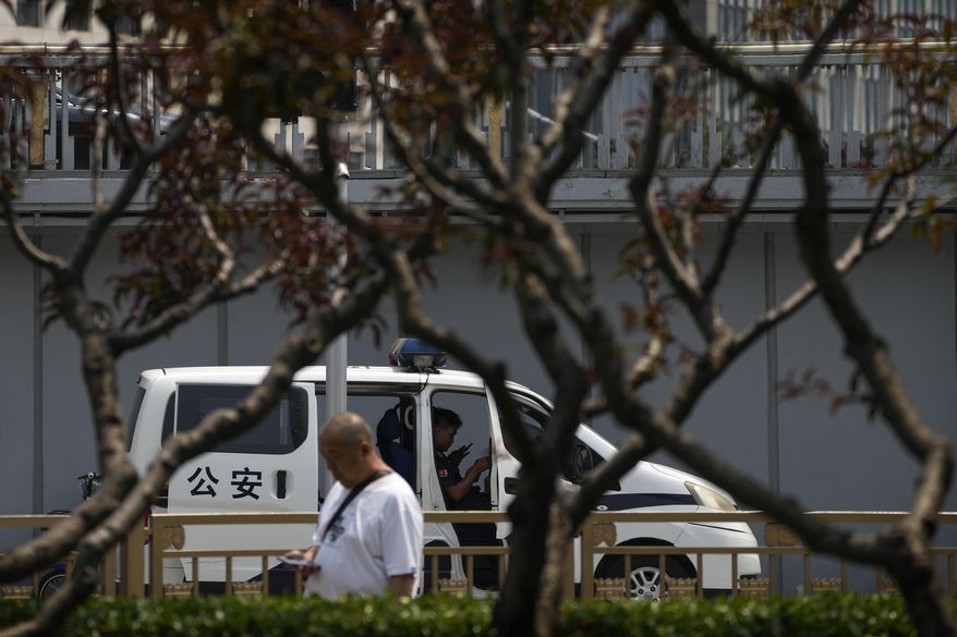 A man walks by a security and a policeman sit inside a police van stationed at a bridge along the Chang'an Avenue in Beijing, Tuesday, June 4, 2024. China has quashed large-scale commemorations of Tuesday's 35th anniversary of Beijing's Tiananmen Square crackdown within its borders. But outside the country, commemorative events have grown increasingly crucial for preserving memories of the 1989 bloodletting, in which government troops opened fire on pro-democracy protesters resulting in hundreds, if not thousands, dead. (AP Photo/Andy Wong)