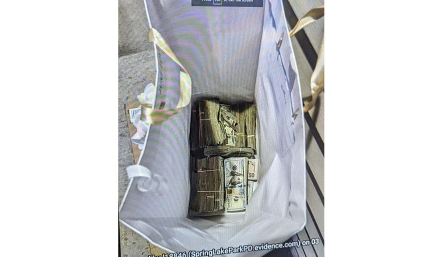 This photo supplied by the U.S. Attorney's Office for Minnesota shows cash from a bag that was left at the home of a juror in a massive fraud case, June 2, 2024, outside Minneapolis, Minn. Authorities have confiscated cellphones and taken all seven defendants into custody as investigators try to determine who attempted to bribe the juror to acquit them on charges of stealing more than $40 million from a program meant to feed children during the pandemic. (U.S. Attorney's Office for Minnesota via AP)