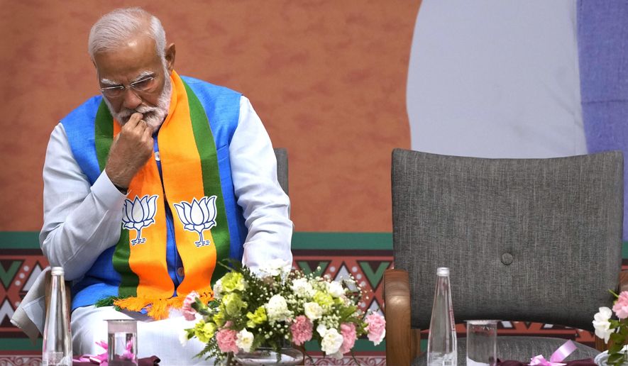 FILE- Indian Prime Minister Narendra Modi listens to Bharatiya Janata Party (BJP) President JP Nadda speak during an event organized to release their party's manifesto in New Delhi, India, April 14, 2024. Since coming to power a decade ago, Prime Minister Narendra Modi has been notorious for big, bold and often snap decisions that he’s found easy to execute thanks to the brute majority he enjoyed in parliament that gave him free reign with minimal checks and balances. Now, Modi faces a style of governance he has little experience in, or desire for. (AP Photo/Manish Swarup, File)