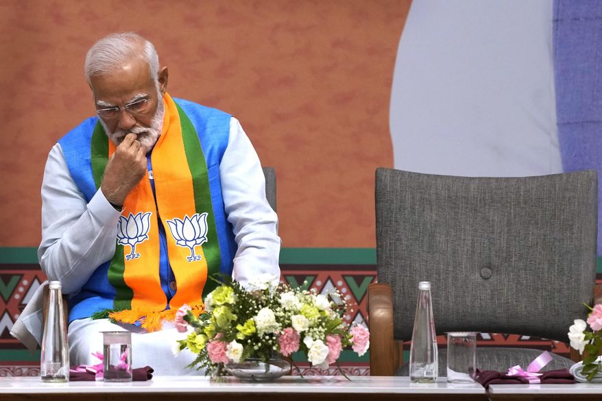 FILE- Indian Prime Minister Narendra Modi listens to Bharatiya Janata Party (BJP) President JP Nadda speak during an event organized to release their party's manifesto in New Delhi, India, April 14, 2024. Since coming to power a decade ago, Prime Minister Narendra Modi has been notorious for big, bold and often snap decisions that he’s found easy to execute thanks to the brute majority he enjoyed in parliament that gave him free reign with minimal checks and balances. Now, Modi faces a style of governance he has little experience in, or desire for. (AP Photo/Manish Swarup, File)