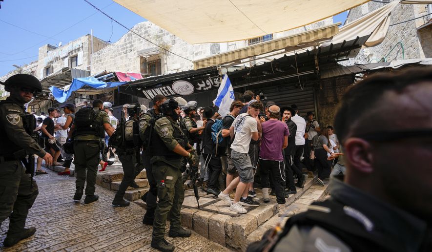 Israeli police officers separate Israelis and Palestinians in a street in the Muslim Quarter of Jerusalem's Old City, shortly before a march through the area by Jewish nationalists in Jerusalem Day, an Israeli holiday celebrating the capture of east Jerusalem in the 1967 Mideast war, Wednesday, June 5, 2024. (AP Photo/Ohad Zwigenberg)