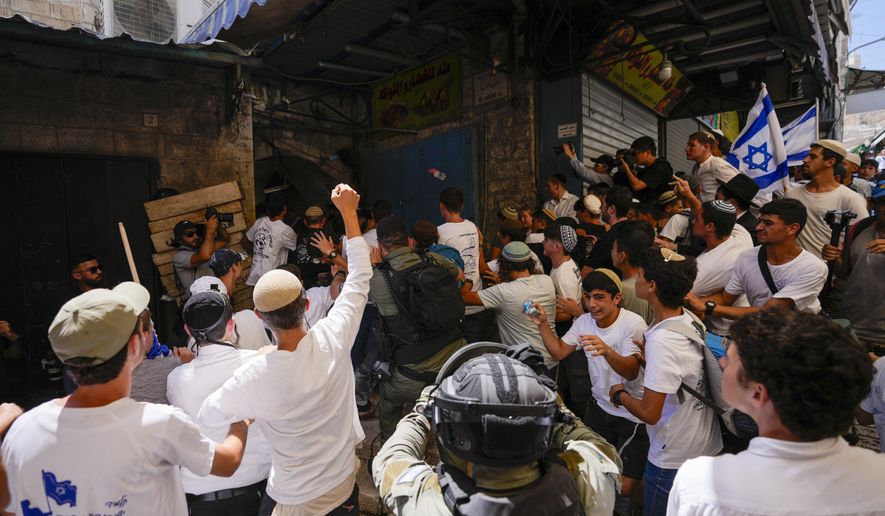 Israeli police officers separate Israelis and Palestinians in a street in the Muslim Quarter of Jerusalem's Old City, shortly before a march through the area by Jewish nationalists in Jerusalem Day, an Israeli holiday celebrating the capture of east Jerusalem in the 1967 Mideast war, Wednesday, June 5, 2024. (AP Photo/Ohad Zwigenberg)