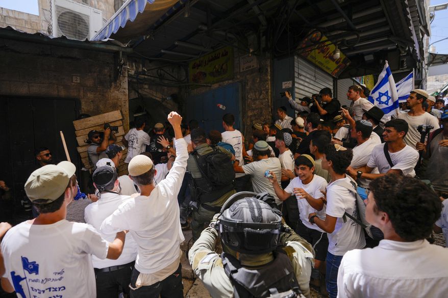 Israeli police officers separate Israelis and Palestinians in a street in the Muslim Quarter of Jerusalem's Old City, shortly before a march through the area by Jewish nationalists in Jerusalem Day, an Israeli holiday celebrating the capture of east Jerusalem in the 1967 Mideast war, Wednesday, June 5, 2024. (AP Photo/Ohad Zwigenberg)