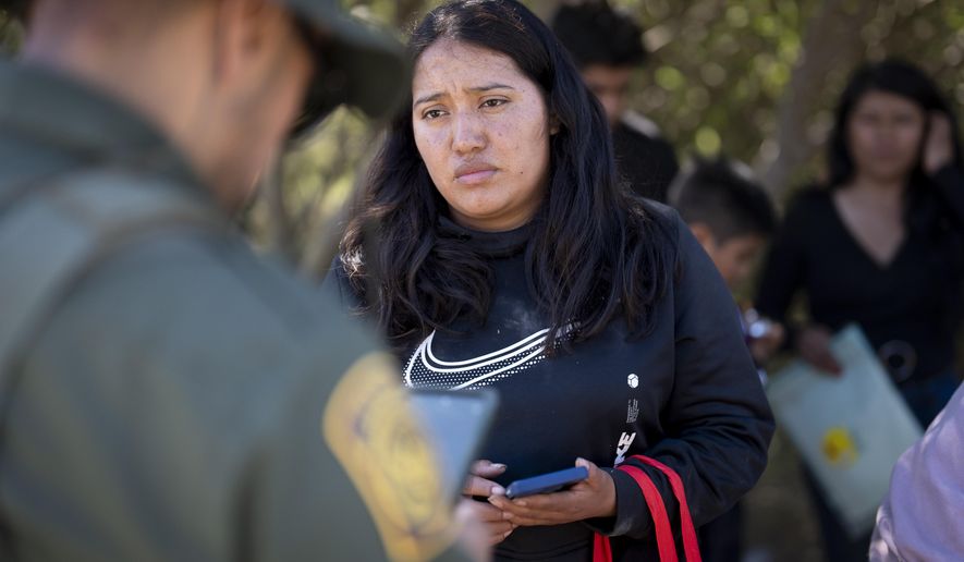 A migrant woman from Mexico talks with a Border Patrol agent before being transported in a van to be processed for asylum, Wednesday, June 5, 2024, near Dulzura, Calif. President Joe Biden on Tuesday unveiled plans to enact immediate significant restrictions on migrants seeking asylum at the U.S.-Mexico border as the White House tries to neutralize immigration as a political liability ahead of the November elections. (AP Photo/Gregory Bull)
