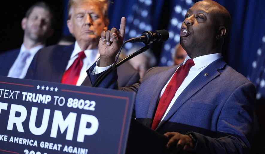 Republican presidential candidate former President Donald Trump listens as Sen. Tim Scott, R-S.C., speaks at a primary election night party at the South Carolina State Fairgrounds in Columbia, S.C., Saturday, Feb. 24, 2024. A top ally of former President Donald Trump — and a potential running mate — is launching a new effort to win over Black and other nonwhite working class voters he argues could be the deciding factor in November's elections. South Carolina Sen. Tim Scott, the only Black Republican in the Senate, will lead a $14 million campaign targeting minority voters in seven key swing states. (AP Photo/Andrew Harnik, File)