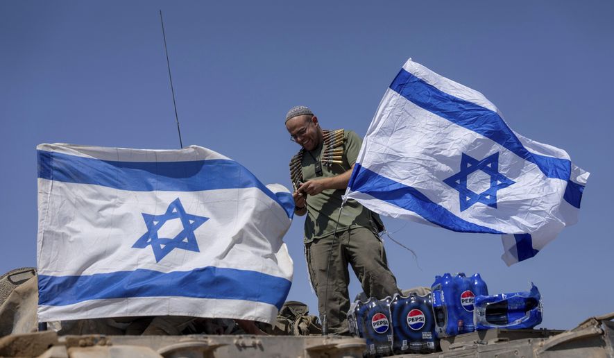 An Israeli soldier seen after he attaches an Israeli flag on top of an armoured personnel carrier (APC) near Israel's border with Gaza, in southern Israel, Thursday, June 6, 2024. (AP Photo/Ohad Zwigenberg)