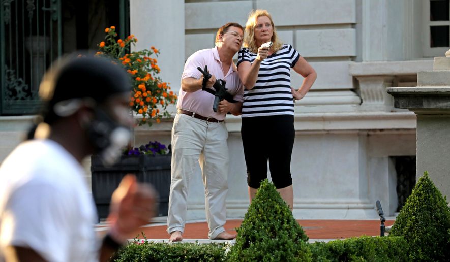 Armed homeowners Mark and Patricia McCloskey stand in front of their house, confronting protesters marching to St. Louis Mayor Lyda Krewson's house in the Central West End of St. Louis, June 28, 2020. A judge has expunged the misdemeanor convictions of the St. Louis couple who pointed guns at racial injustice protesters outside their mansion in 2020. Now, they say, they want their guns back. (Laurie Skrivan/St. Louis Post-Dispatch via AP, File)
