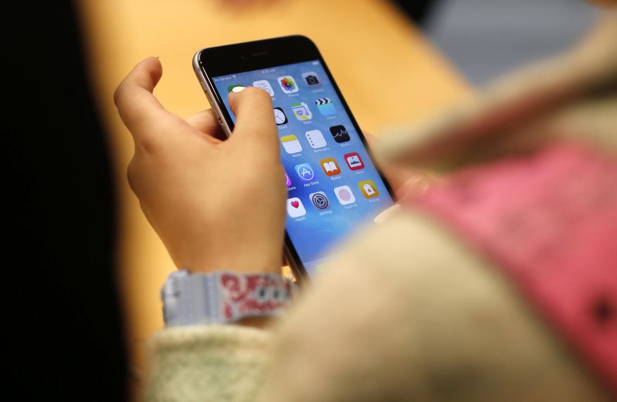 A child holds an iPhone at an Apple store on Sept. 25, 2015, in Chicago. Parents — and even some teens themselves — are growing increasingly concerned about the effects of social media use on young people. (AP Photo/Kiichiro Sato, File)