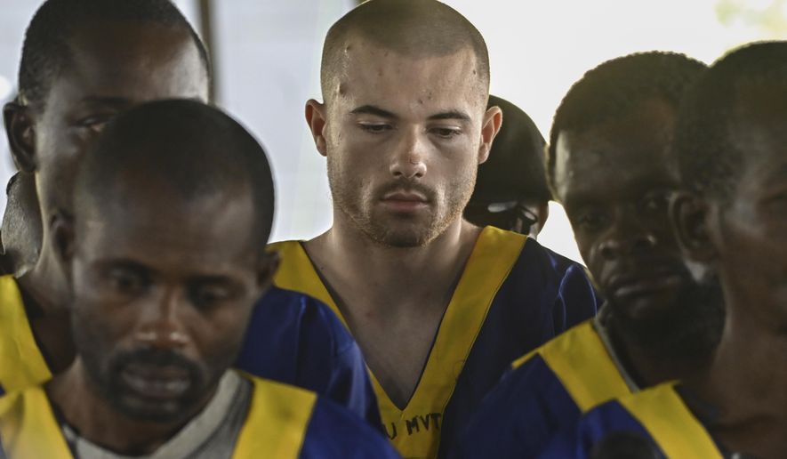 American Tyler Thompson Jr, center, sits in court in Kinshasa, Friday, June 7, 2024. Three Americans accused of a role in last month's attempted coup in Congo appeared in court in Kinshasa on Friday, among a total of 53 defendants who were lined up on plastic chairs before the judge on the first day of the hearing. (AP Photo/Samy Ntumba Shambuyi)