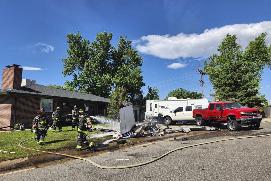 In this image provided by the Arvada, Colo. Police Department, emergency personnel work at the scene of small plane crash, Friday morning, June 7, 2024, in Arvada, Colo. Four people were hospitalized after a small plane crashed in the front yard of a suburban Denver home on Friday, authorities said. (Arvada Police Department via AP)