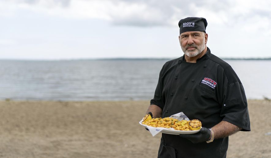 Executive chef John Bordieri is photographed with a dish of calamari outside Iggy's Boardwalk restaurant Friday, June 7, 2024, in Warwick, R.I. This year, the "calamari comeback" chef might not be coming back. Bordieri became known as the "calamari ninja" for standing wordlessly, clad head-to-toe in black, and holding a platter of sauteed squid during a video roll call of states that nominated Joe Biden during the 2020 Democratic National Convention. But he now says he hasn't heard from state or national leaders about a repeat performance at this summer's party's convention in Chicago. (AP Photo/David Goldman)