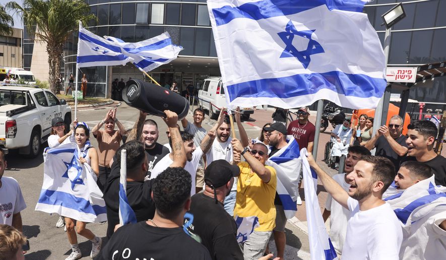 People wave Israeli flags as they celebrate after hostages who were kidnapped in a Hamas-led attack on Oct. 7. were rescued from Gaza Strip, at the Sheba Medical Center in Ramat Gan, Israel, Saturday, June 8, 2024. Israel says it has rescued four hostages who were kidnapped in a Hamas-led attack on Oct. 7. It is the largest such hostage recovery operation since the war with Hamas began in Gaza. (AP Photo/Tomer Appelbaum)