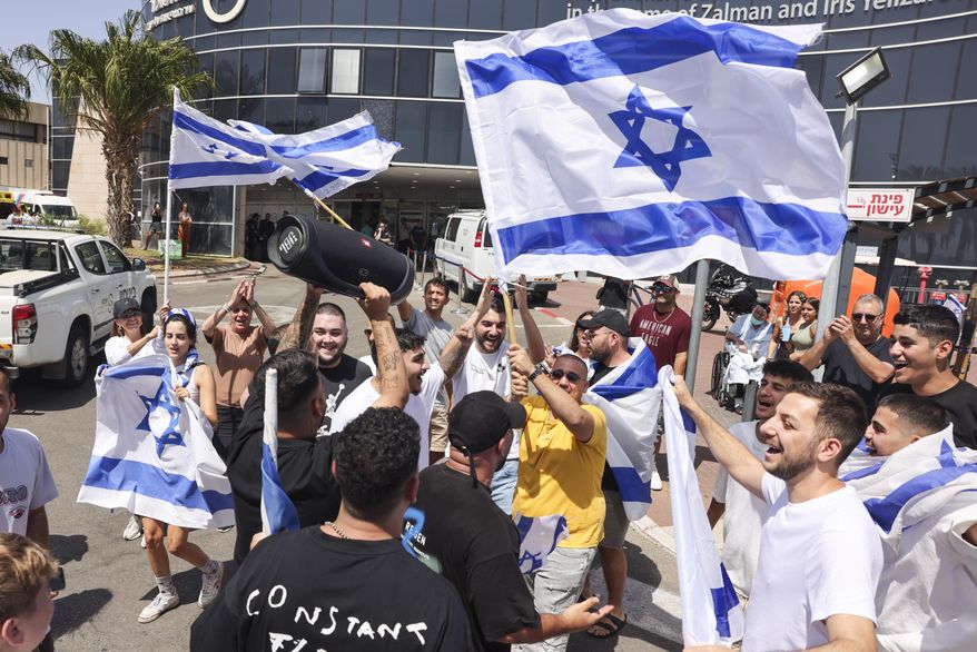 People wave Israeli flags as they celebrate after hostages who were kidnapped in a Hamas-led attack on Oct. 7. were rescued from Gaza Strip, at the Sheba Medical Center in Ramat Gan, Israel, Saturday, June 8, 2024. Israel says it has rescued four hostages who were kidnapped in a Hamas-led attack on Oct. 7. It is the largest such hostage recovery operation since the war with Hamas began in Gaza. (AP Photo/Tomer Appelbaum)
